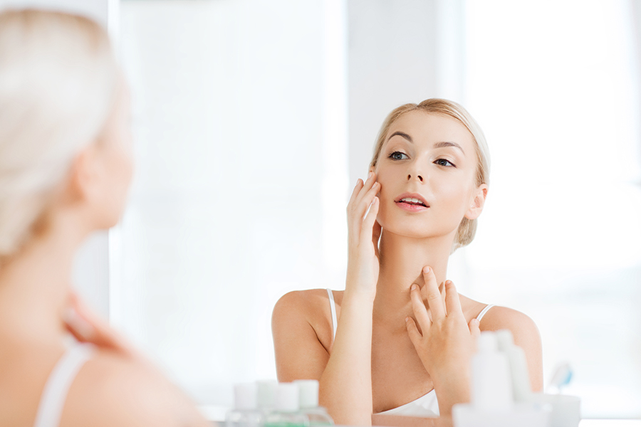 Happy Young Woman Checking Her Chin And Neck In The Mirror