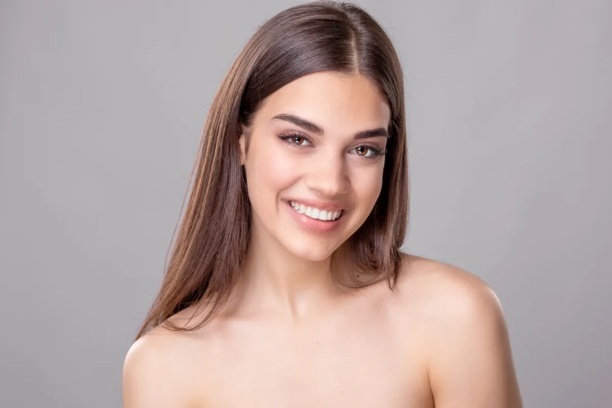 smiling pretty brunette woman on gray background