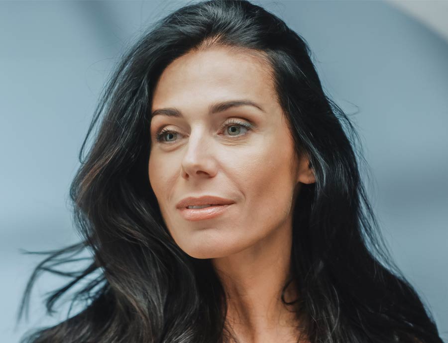 Photo of a black haired woman looking at herself in the mirror