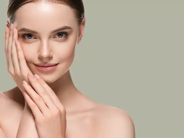Woman with smooth, healthy skin touching her face after facial rejuvenation treatment at Des Moines Plastic Surgery